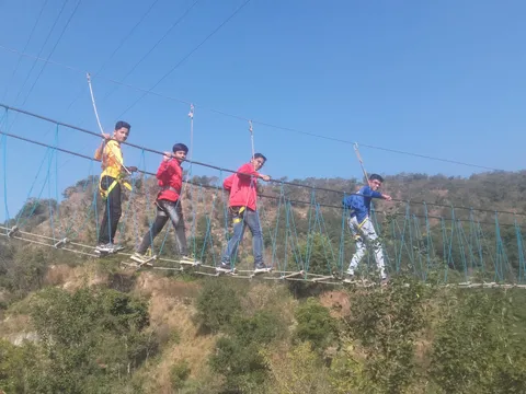 A student crossing a high-ropes bridge